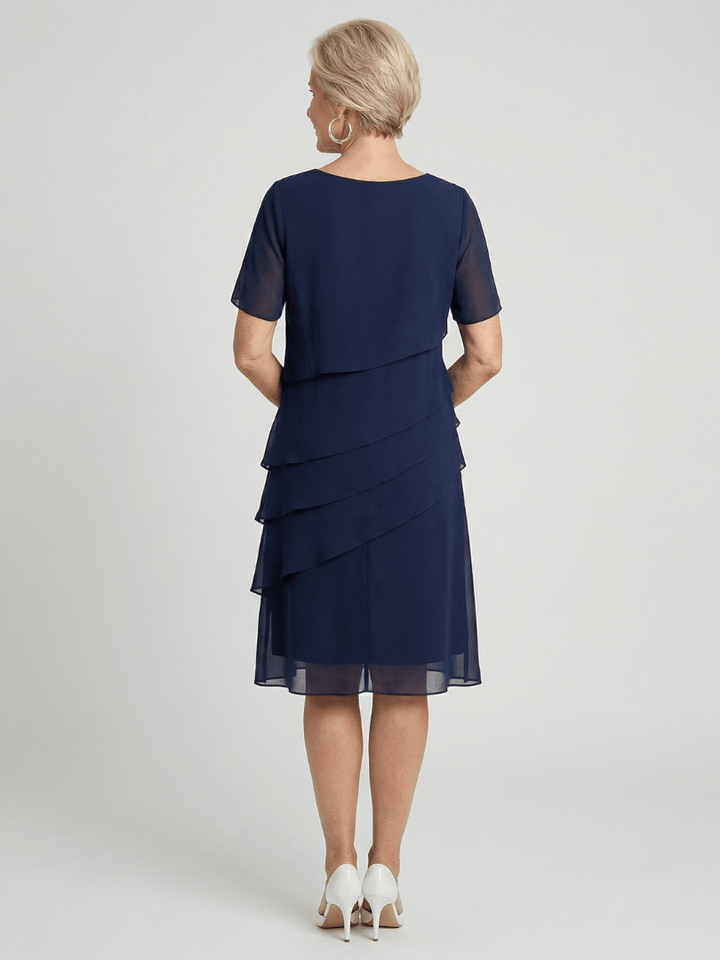 Emma & Rose Cape Town Orson™ Contour Knee Length Dress in stylish fabric, shown on a mannequin with elegant draping and fitted silhouette.