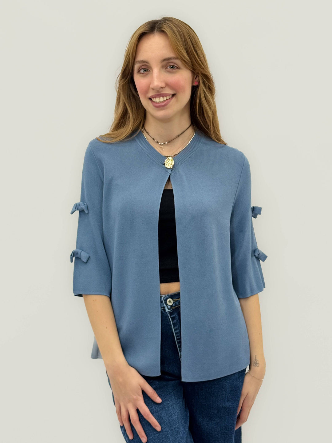 Emma & Rose Cape Town Lightweight™ cardigan with bow details, soft knit fabric, and a cozy fit, displayed on a hanger.